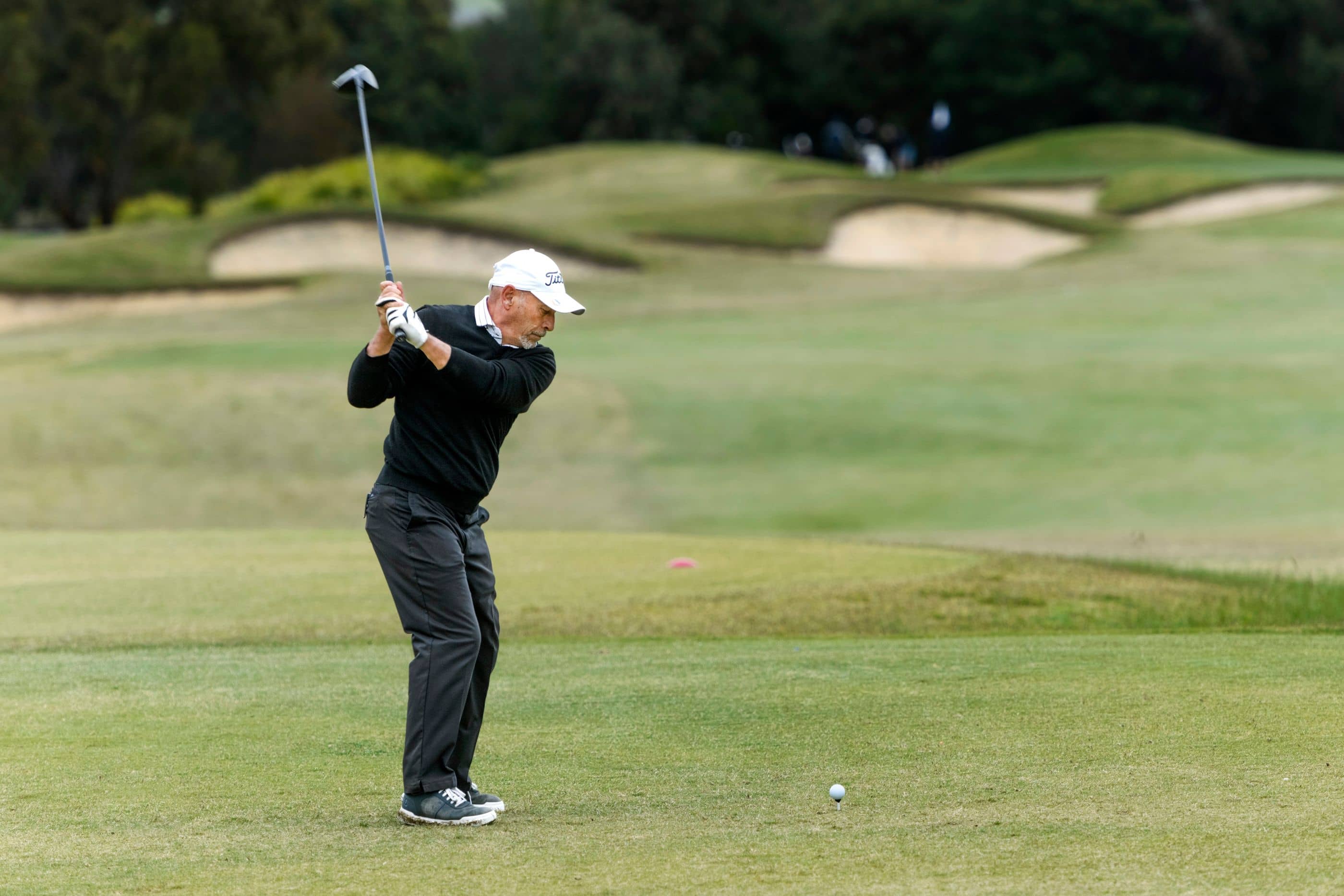 A man is mid swing on the golf course