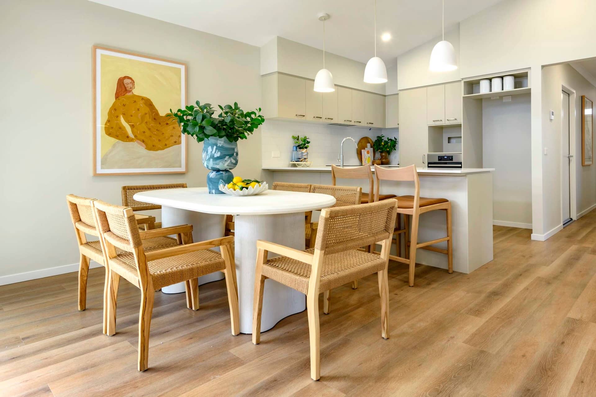 Dining area and kitchen in an Ingenia Lifestyle community home, featuring a white table with woven chairs and pendant lights.