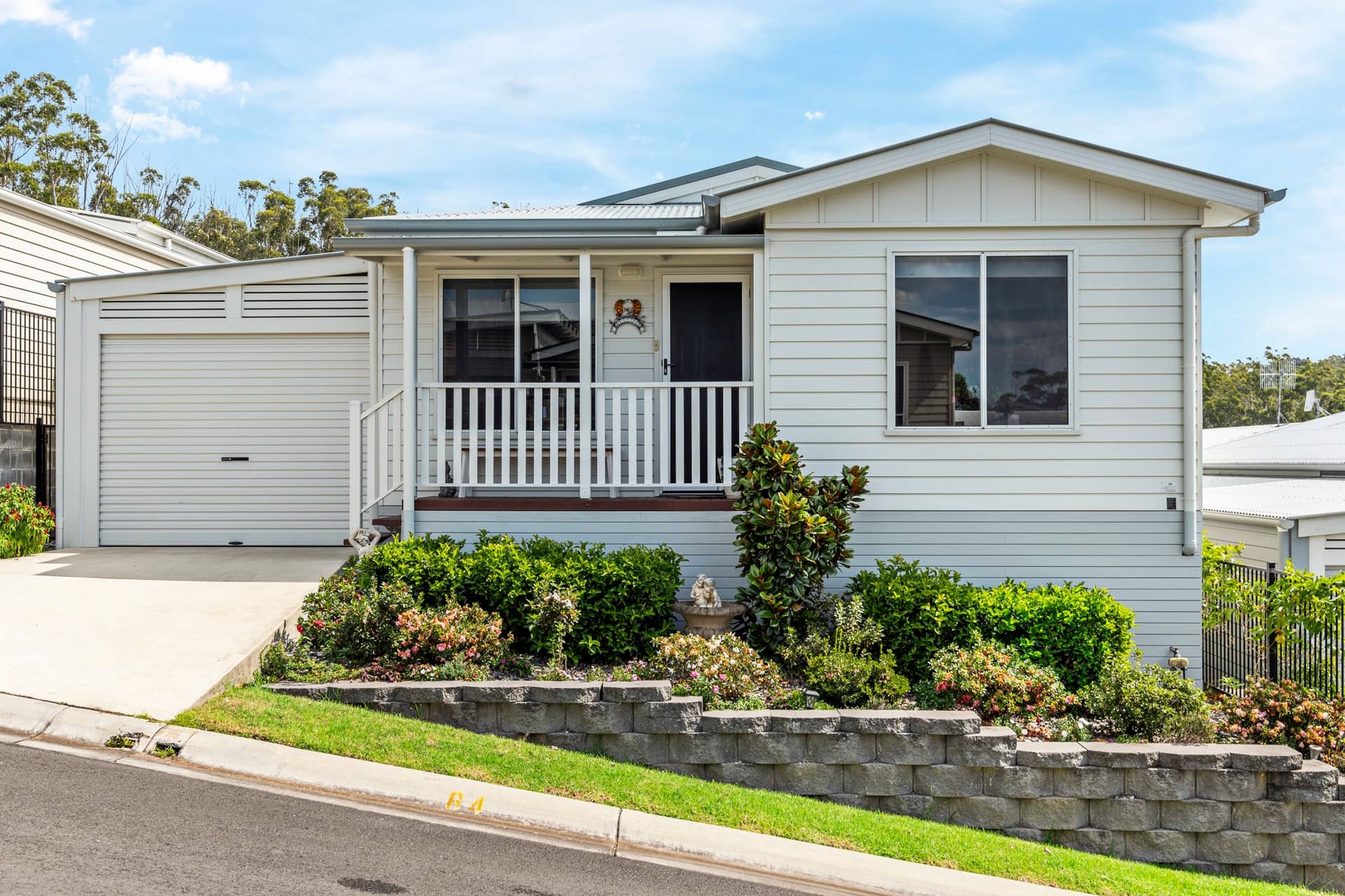 Exterior of an Ingenia Lifestyle land-lease home with a white facade, front porch, garage, and landscaped garden.