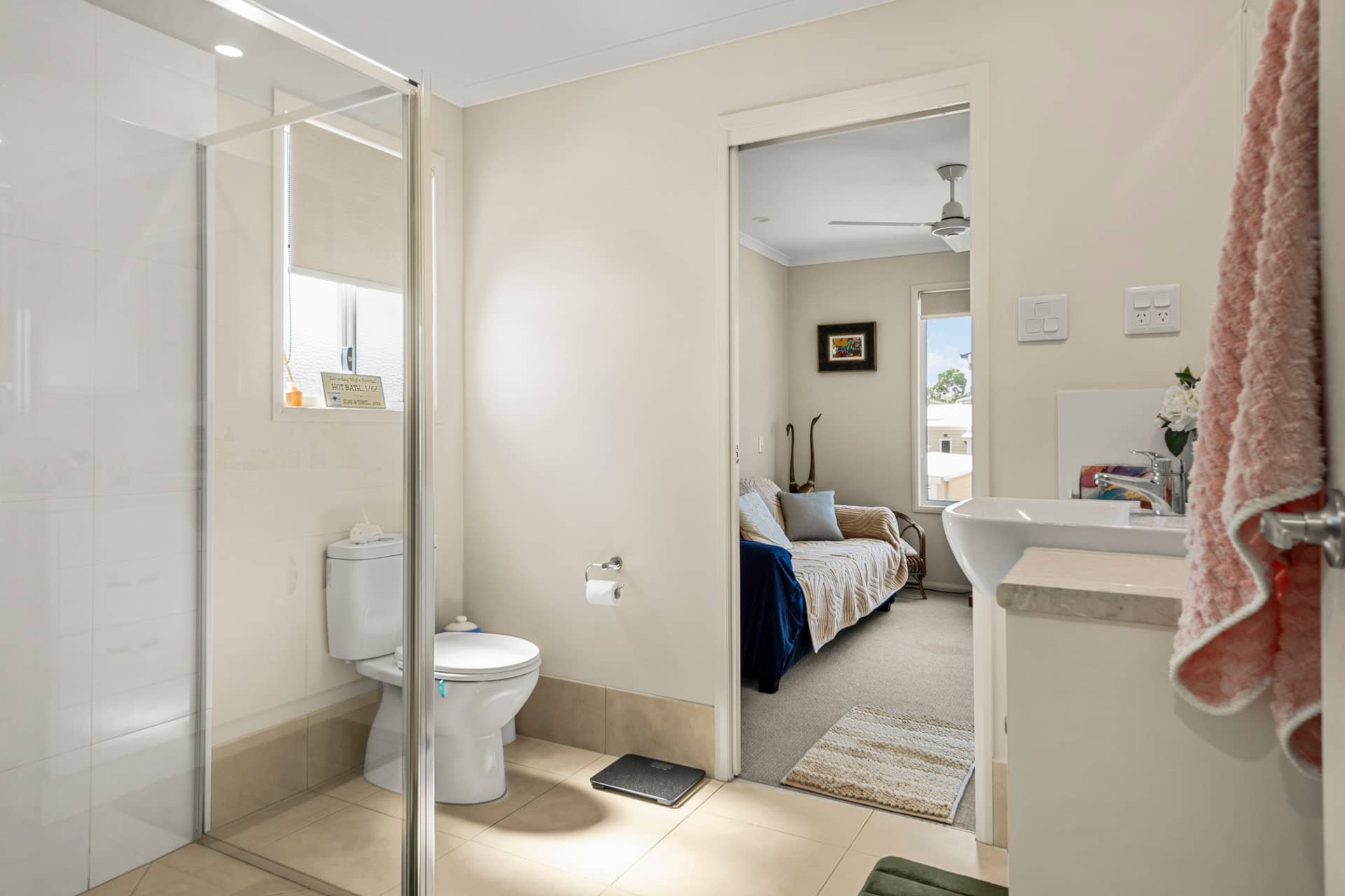 Bathroom in an Ingenia Lifestyle home with a walk-in shower, toilet, and sink, connected to a carpeted living space.