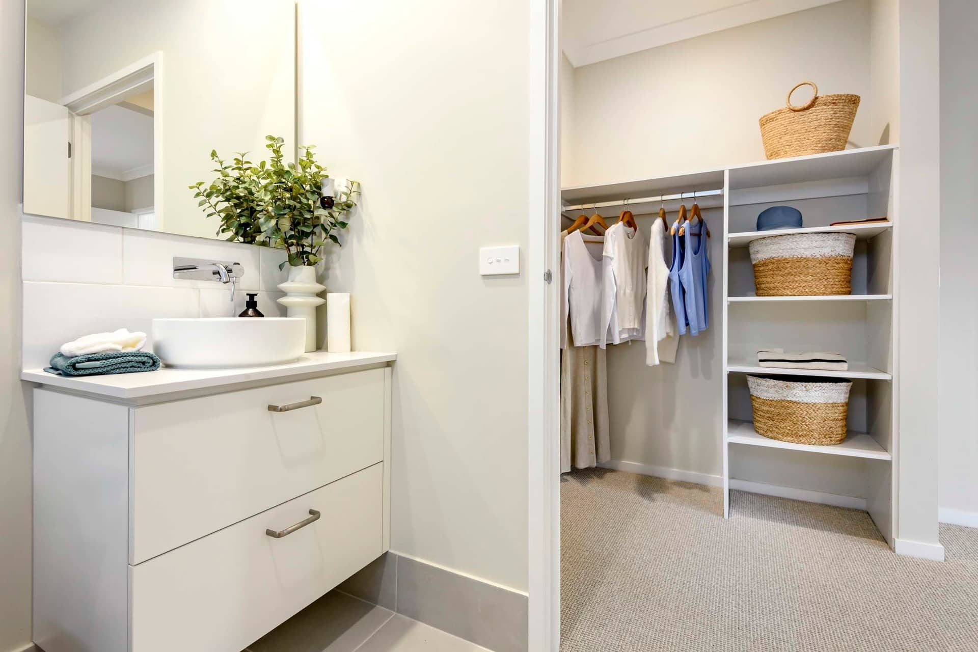 Bathroom vanity with vessel sink and walk-in closet with clothing and baskets.