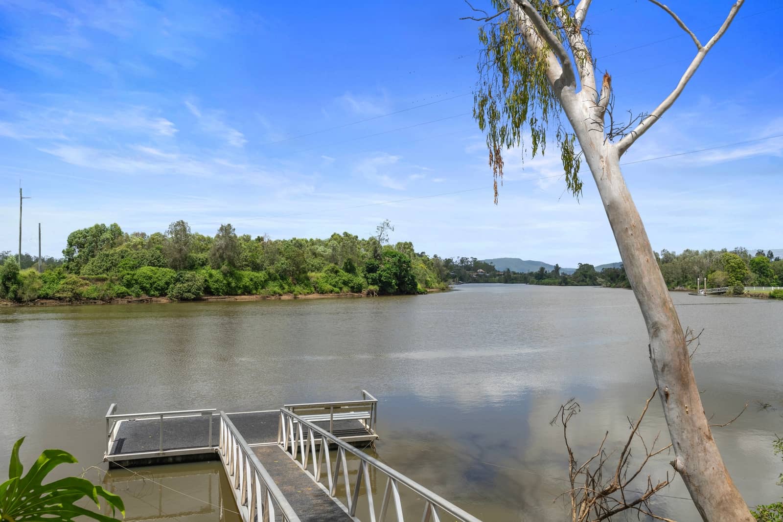 A metal pontoon on a wide river with tree-lined banks and hills. A shared amenity for an Ingenia Lifestyle community.