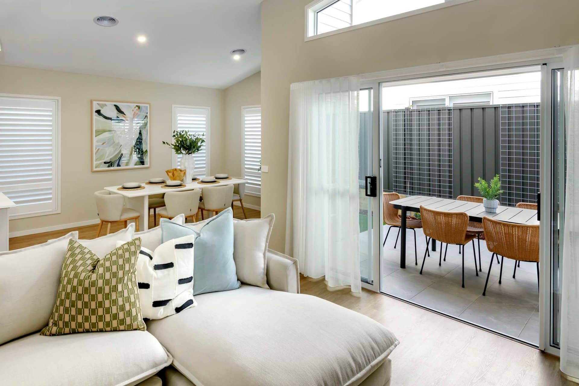 Interior view of a living room with a chaise lounge, leading to an outdoor patio with a dining set.