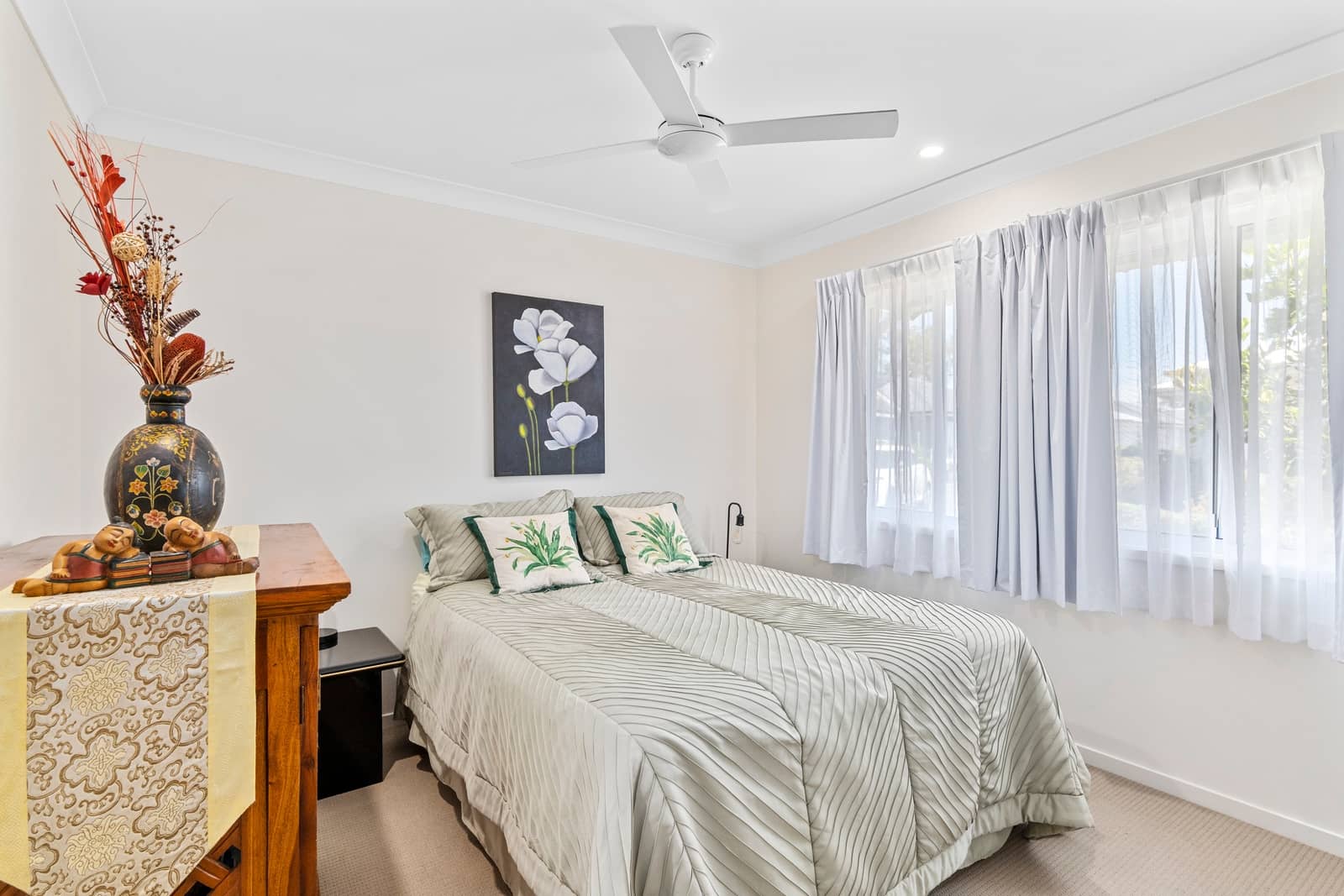 Bedroom with a bed, ceiling fan, and decorative items.