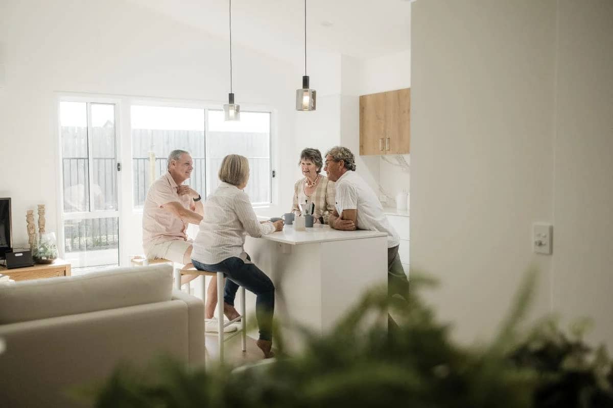 Residents socialising around a kitchen island in a modern Ingenia Lifestyle community home.