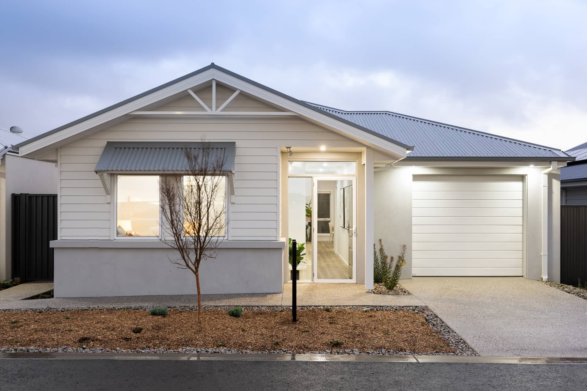 Ingenia Lifestyle home with a white exterior, grey roof, single garage and landscaped garden beds.