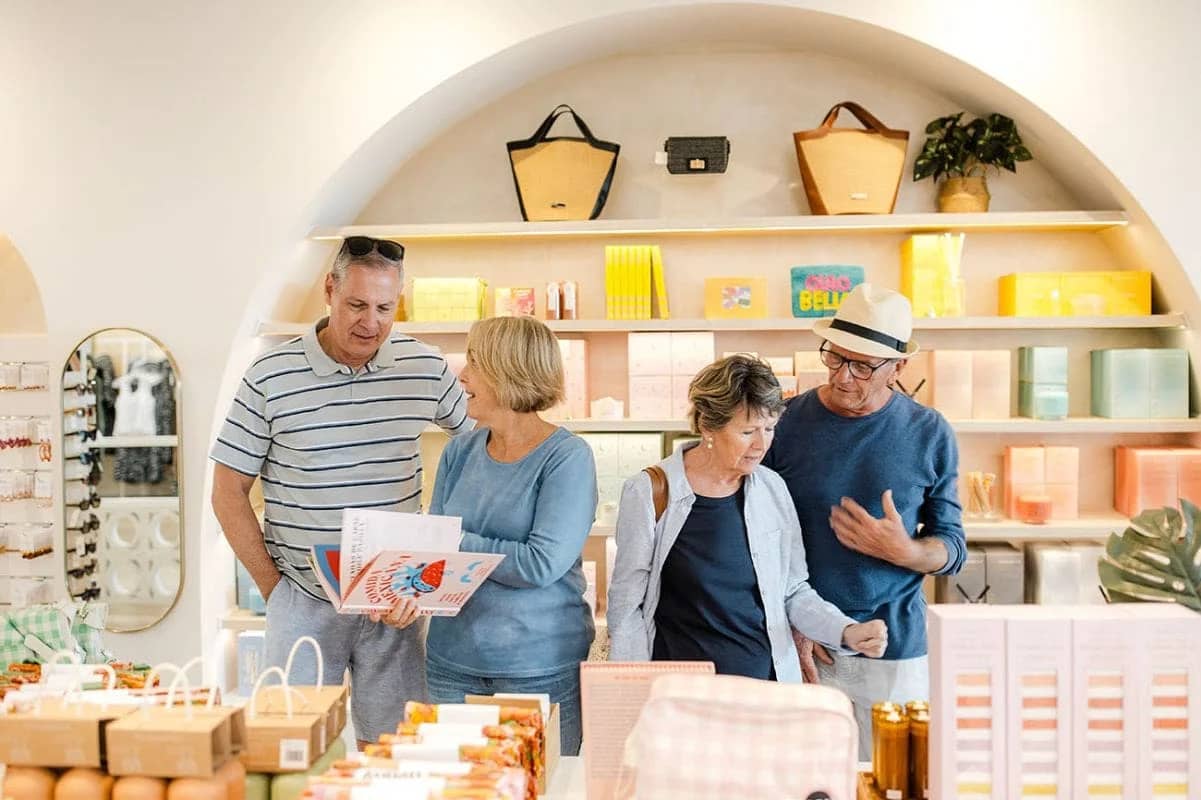 Four individuals shopping and conversing in a brightly lit store, with shelves of various products.