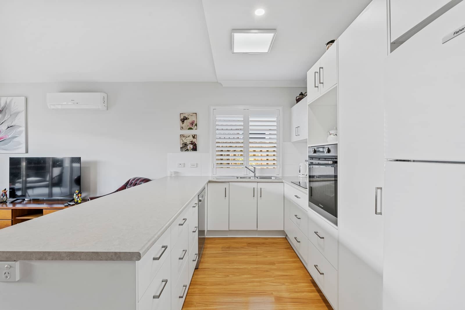 Modern white kitchen with island and stainless steel appliances, in an Ingenia Lifestyle community home.