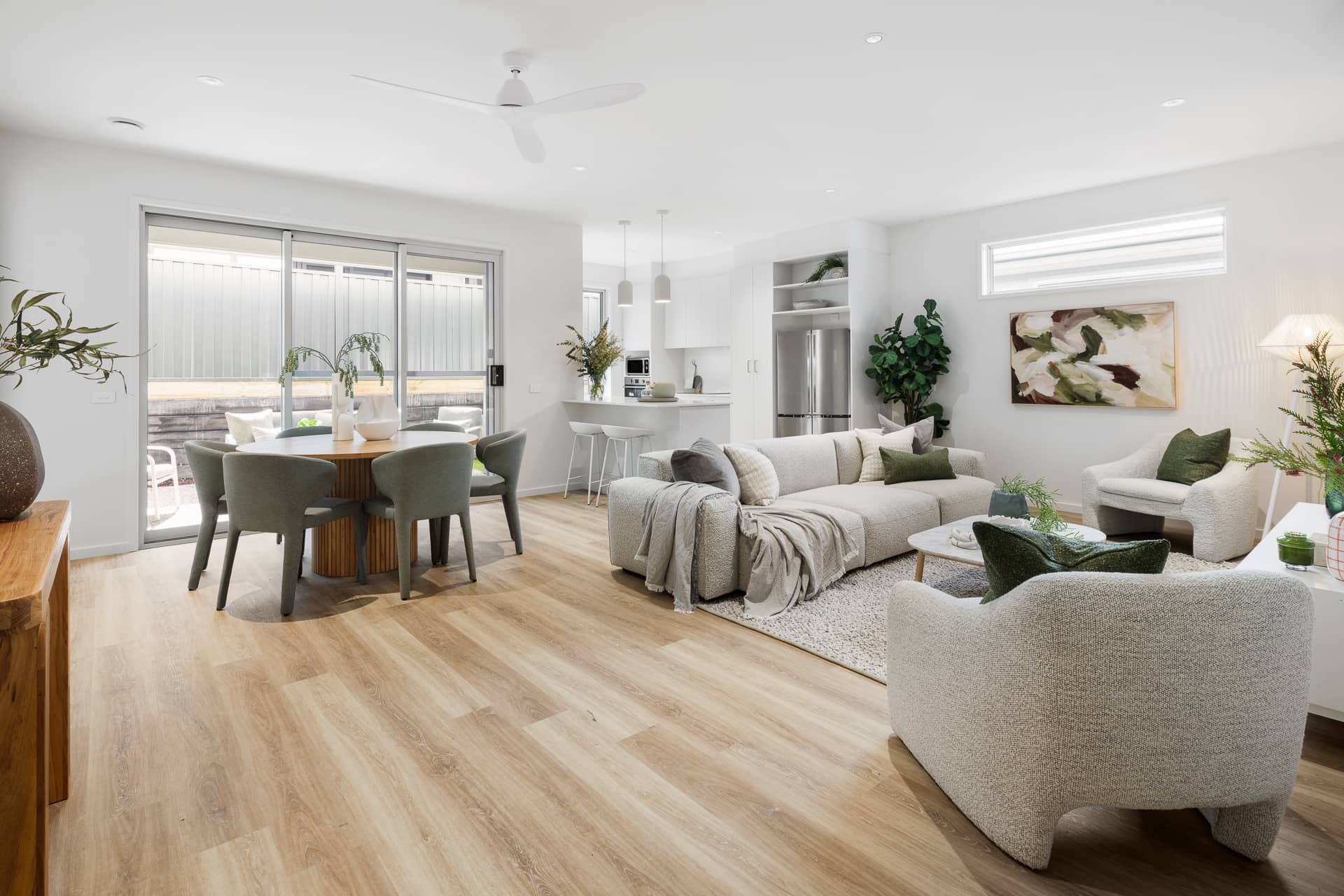 Ingenia Lifestyle home: open-plan living, dining, and kitchen with light wood-look flooring and white cabinetry.