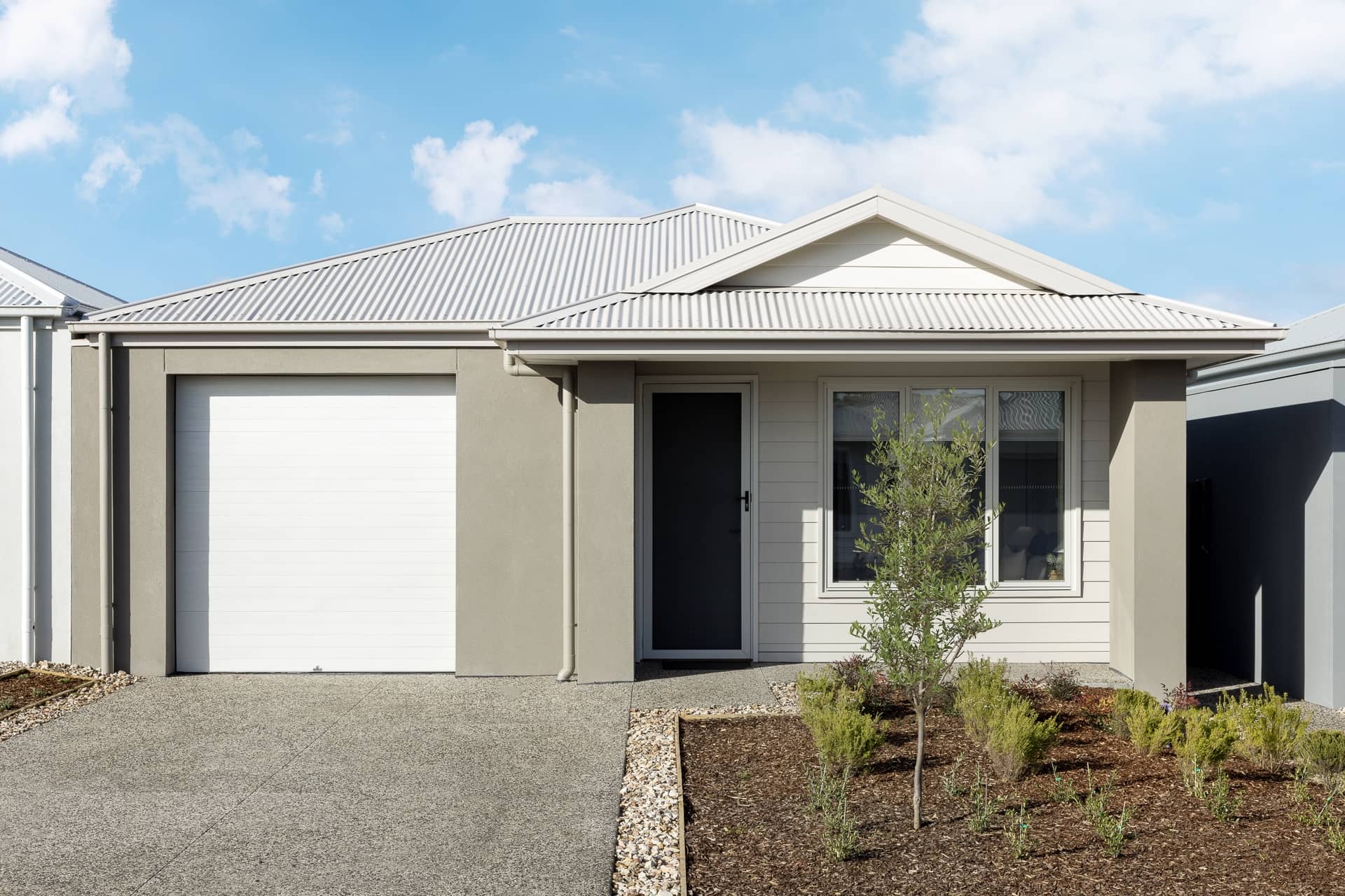 Exterior of a modern single-story Ingenia Lifestyle home with a white garage, light grey facade, and landscaped front garden.