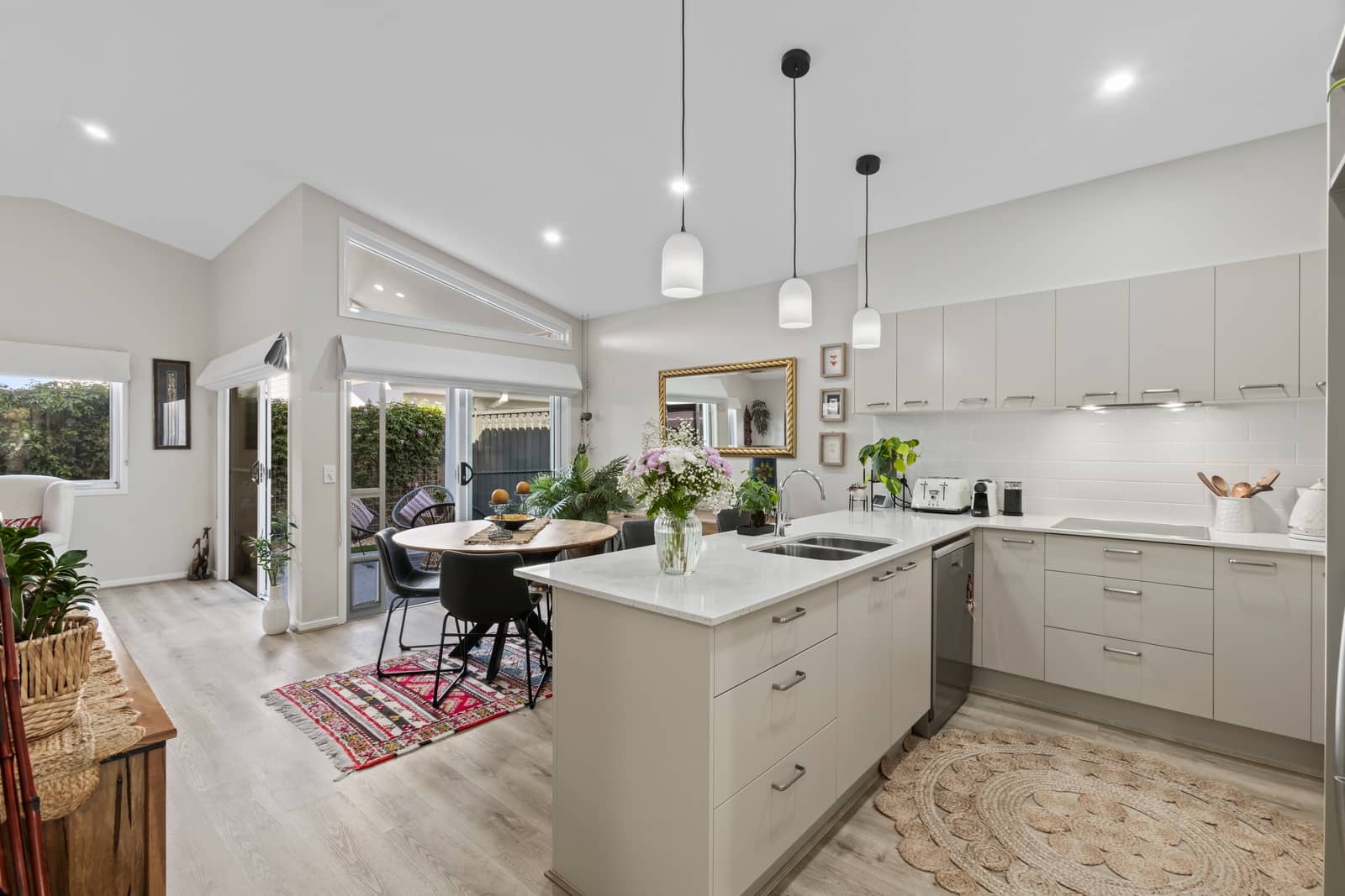 Modern kitchen with island, dining area, and view of outdoor space in an Ingenia Lifestyle community.
