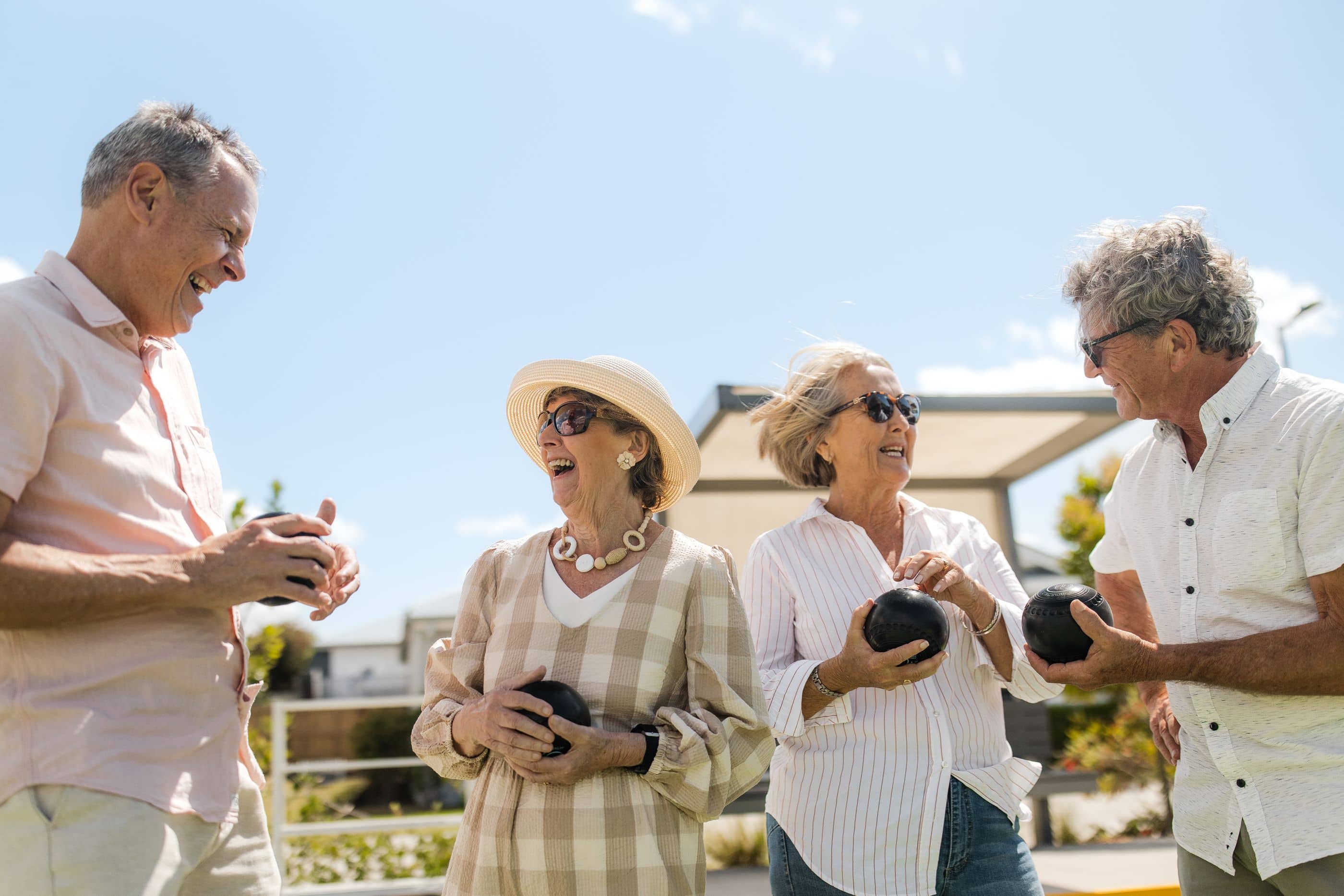 Four people holding lawn bowls, laughing together at an Ingenia Lifestyle community facility.