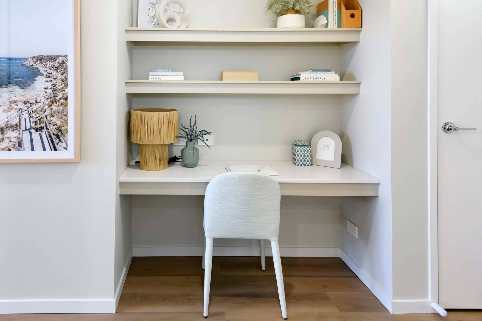 Desk area with shelves, lamp, chair and framed coastal artwork in an Ingenia Lifestyle home.