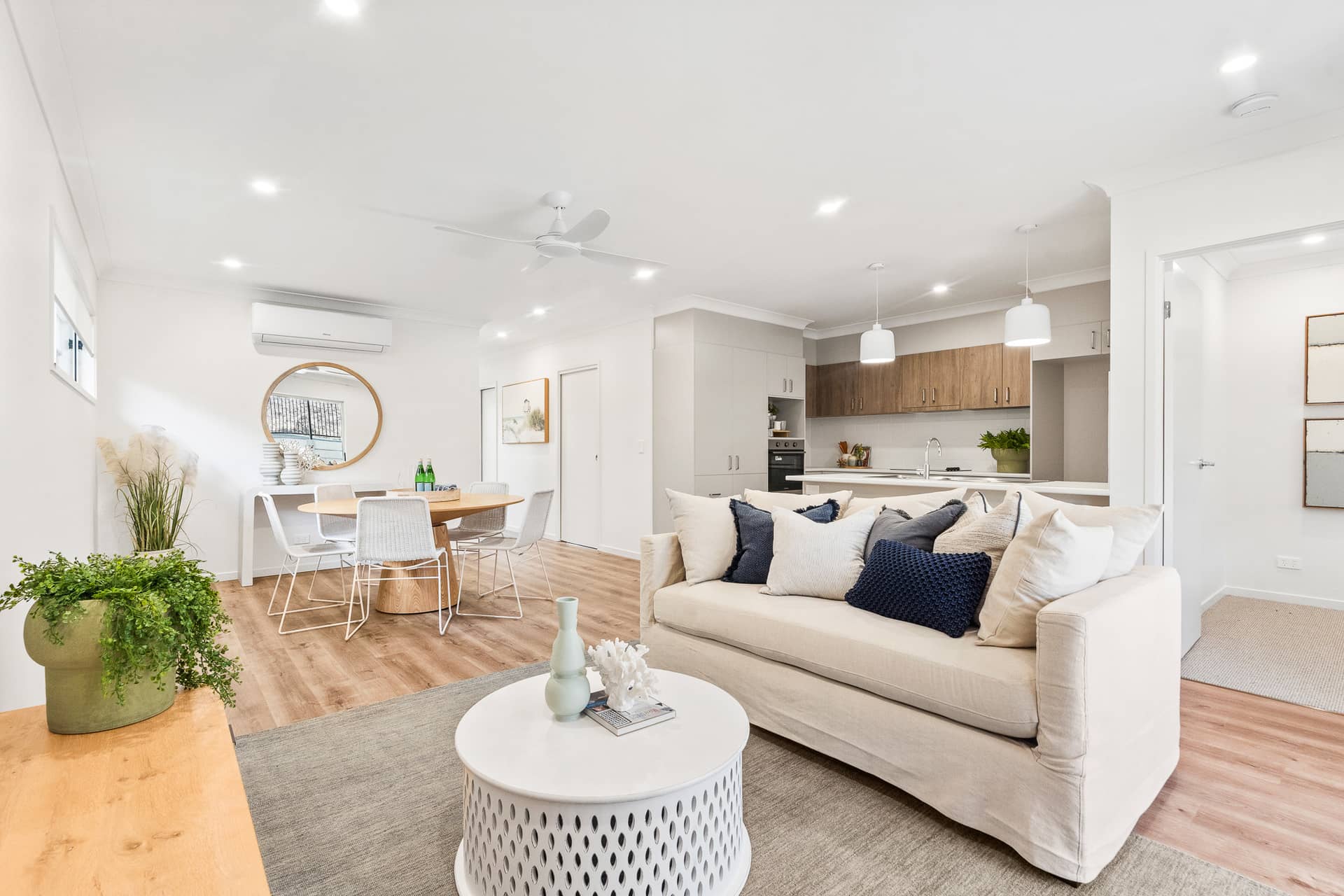 Open-plan living area with a sofa, coffee table, dining table, and kitchen in an Ingenia Lifestyle community.