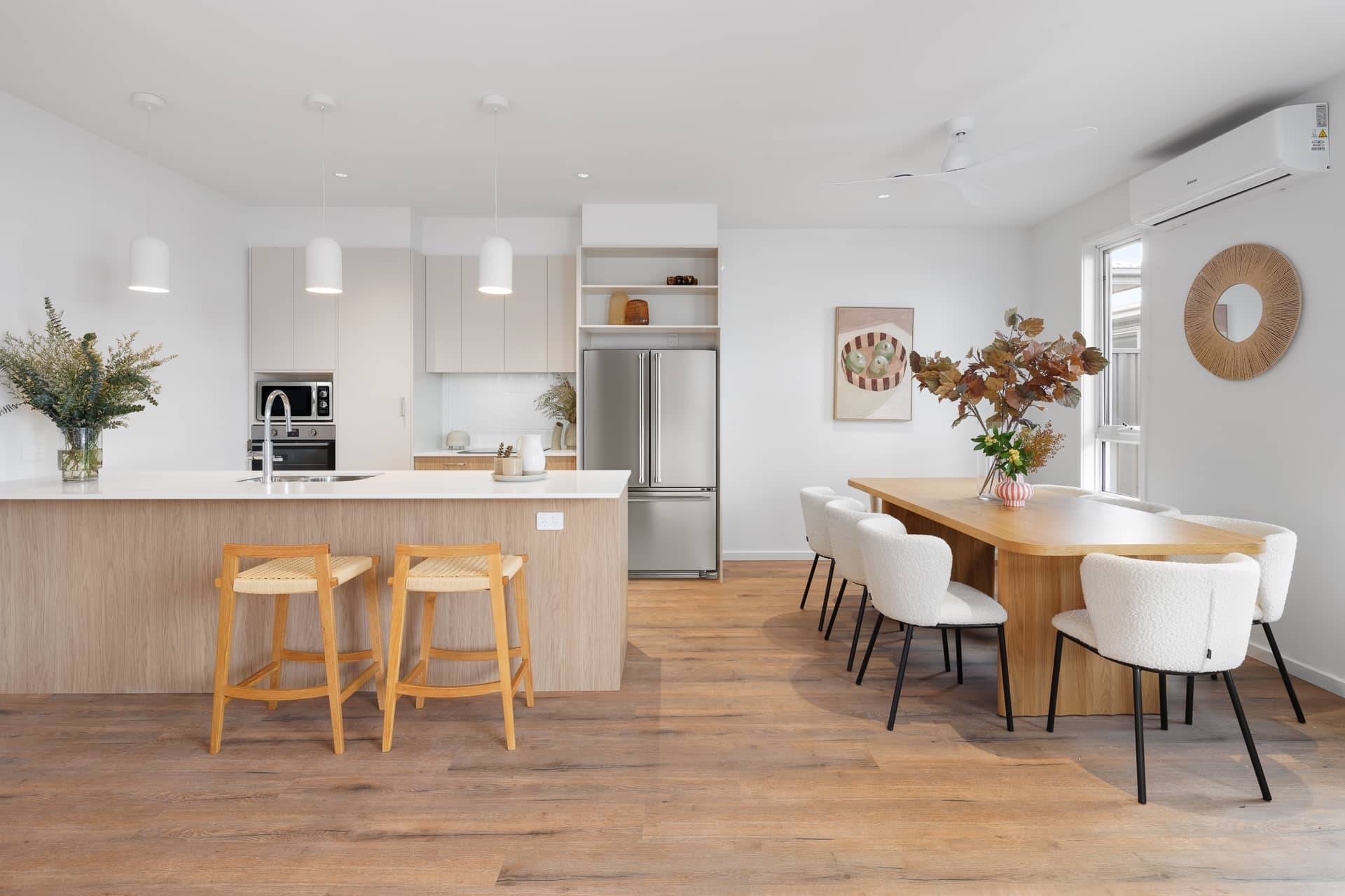 Open-plan kitchen and dining area of an Ingenia Lifestyle home, featuring a modern kitchen island, dining table with seating, and wooden flooring.
