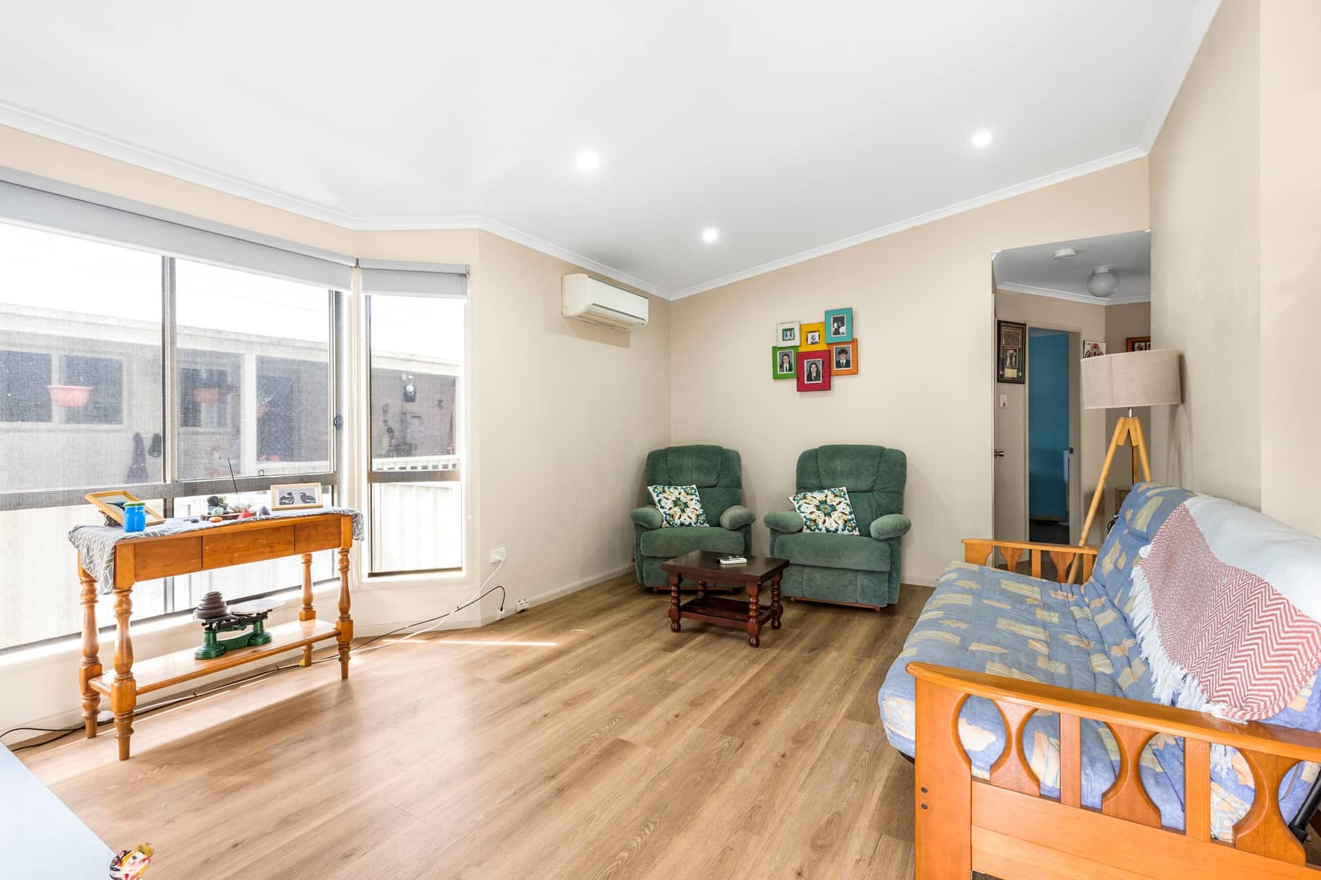Bright living room of an Ingenia Lifestyle home with wood-look flooring, large windows, two armchairs, and a sofa.