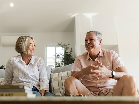 Over 55s couple sitting down on the couch planning their future purchase